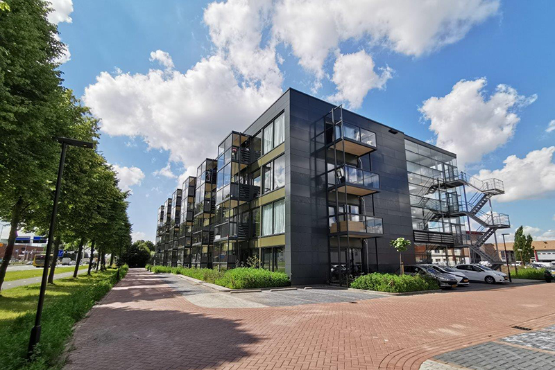 Vue éloignée d'un bâtiment revêtu d'un bardage foncé en bois composite Trespa®